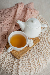 A mug of hot tea, a teapot, a wooden stand on an ottoman. Cozy autumn. Winter breakfast. Cotton.