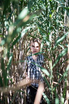 Boy stands in the middle of tall grass stalks
