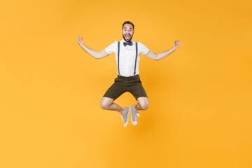 Fototapeta na wymiar Full length portrait of excited young bearded man 20s wearing white shirt suspender shorts posing jumping hold hands in yoga gesture, relaxing meditating isolated on bright yellow background studio.