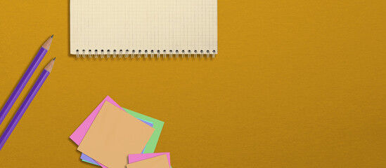 Pencils and notebook on the table, top view, school supplies. Yellow background