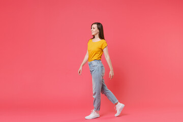 Fototapeta na wymiar Full length portrait side view of smiling beautiful attractive young brunette woman 20s wearing yellow casual t-shirt posing walking going looking aside isolated on pink color wall background studio.