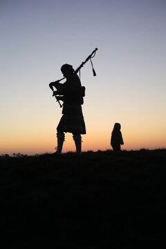 Silhouette of a bagpipe player at sunset