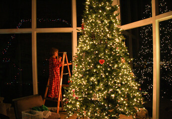 Little girl putting ornaments on the Christmas tree