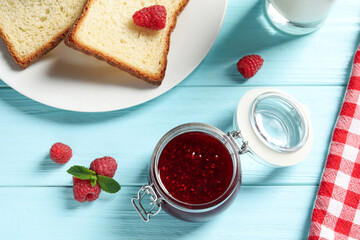 Sweet raspberry jam and toasts for breakfast on turquoise wooden table, flat lay