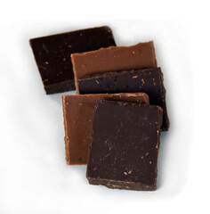 Chocolate cubes, milk and dark, bitter chocolate bar pieces on white background, close-up view.