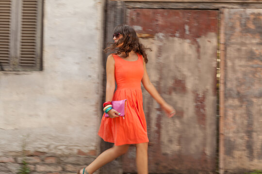 Woman in an orange dress walking down the street.