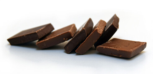 Chocolate cubes, milk and dark, bitter chocolate bar pieces on white background, close-up view.