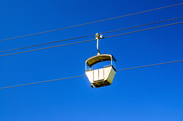 Fototapeta na wymiar Cable car on rope of cableway, blue clear sky background in sunny summer day, from Rudesheim am Rhein town to Roseneck mount above vineyards fields, State of Hesse, Germany