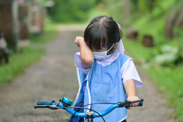 Fototapeta na wymiar little girl crying while sitting on bicycle at outdoors road