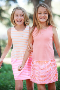 Happy fraternal twin sisters wearing dresses laughing