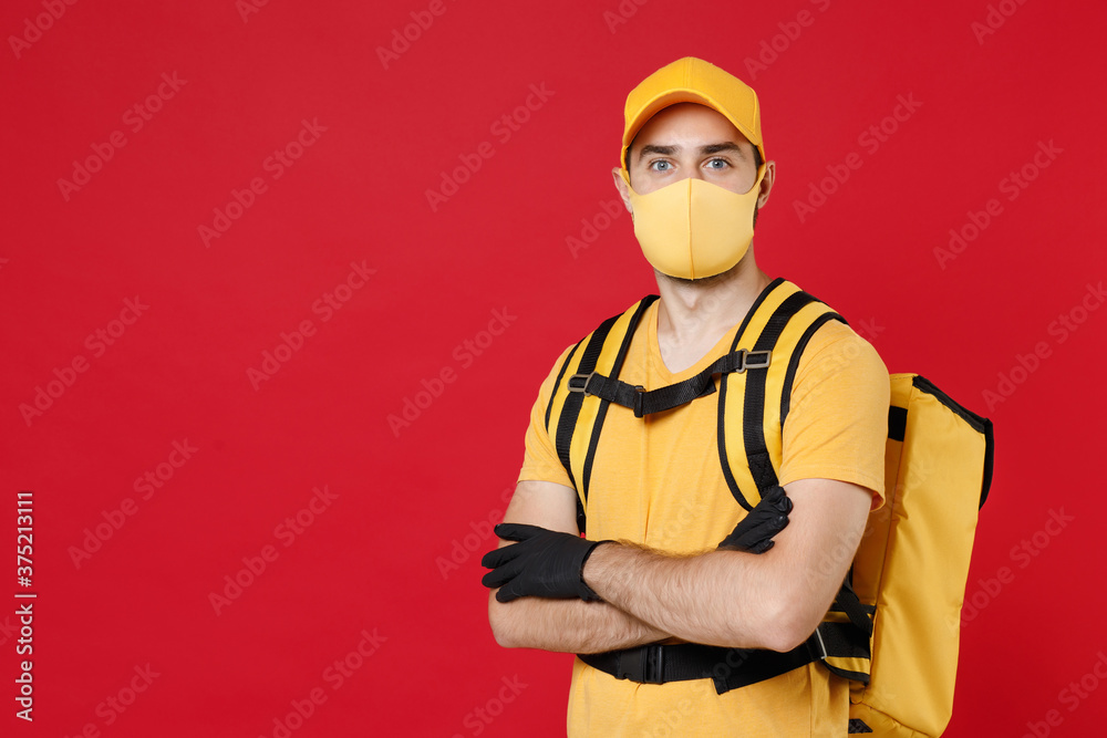 Wall mural delivery employee man in yellow cap face mask gloves t-shirt uniform thermal bag backpack with food 