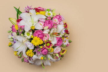 Top view of bunch of flowers, on beige background. Copy space.