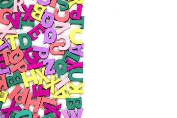 Multicolored background of wooden letters of the Latin alphabet with free space on the right on white background. Blank to insert text. Concept: back to school, literacy and reading, language learning