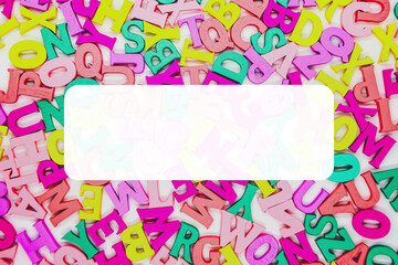 Multicolored background of wooden letters of the Latin alphabet. Top view, abstract texture with letters. White bar in the center for inserting text. Concept: back to school, literacy and reading.