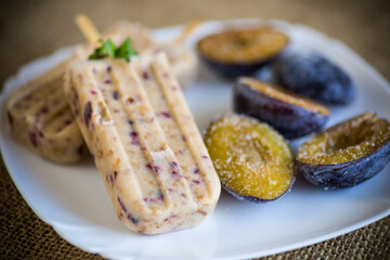 plum sweet homemade ice cream on a stick with slices of plum inside, in a plate