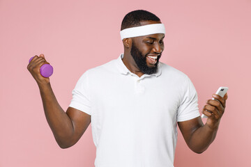 Smiling young bearded african american fitness sports man 20s in headband t-shirt doing exercise...