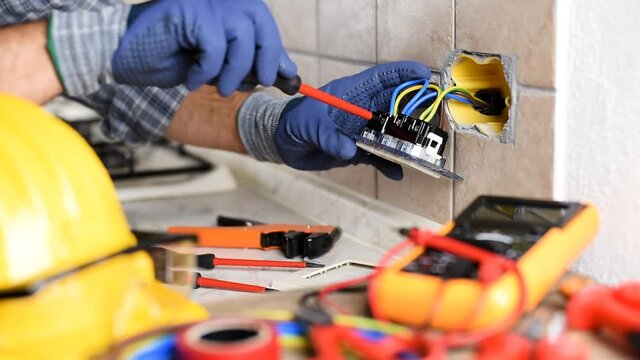 Electrician at work with screwdriver fixes the cable in the sockets of a residential electrical system. Construction industry. Footage.