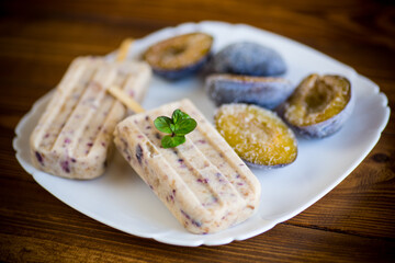 plum sweet homemade ice cream on a stick with slices of plum inside, in a plate