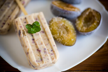 plum sweet homemade ice cream on a stick with slices of plum inside, in a plate