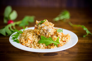 boiled bulgur groats with vegetables and meatballs in a plate