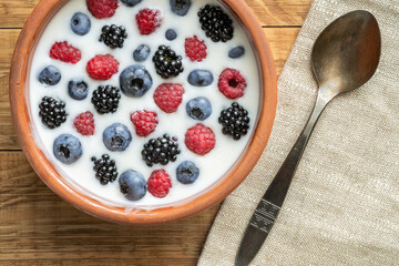 Yogurt with blueberries, raspberries, blackberries, flax seeds in a clay bowl. Served vegetarian dish. Healthy breakfast, healthy food. Background for the menu of restaurants, cafes.