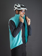 A cyclist puts on a blue jacket before riding a bike.