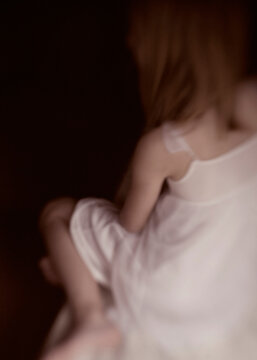 Girl facing darkness showing back only in white dress