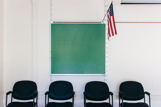 classroom with blackboard, chairs, and American flag
