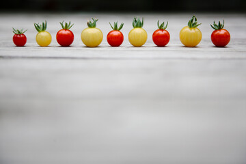 A row of tiny tomatoes on a wooden background.