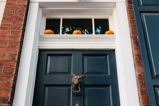Three tiny pumpkins decorate a front door.