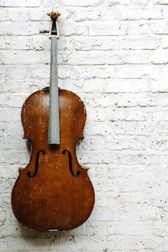 Old weathered cello against a textured white wall