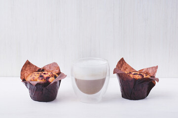 Blueberry muffin in brown paperand glass with tasty chocolate milk on white background, Homemade baking. Simple and comfortable food