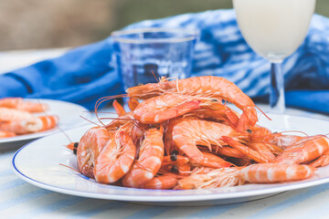 Plate with prawns and a glass with aperitif on a blue and white table