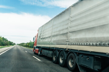 Fototapeta na wymiar truck with container drives along asphalt road, moving away to point on horizon to right of camera.
