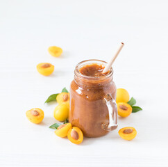 Yellow plum smoothie in a glass jar with a bamboo straw on a light background