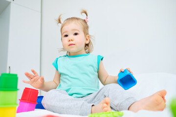 Caucasian toddler sitting on the bed among toys