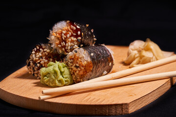 Sushi with chopsticks on black background
