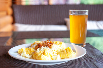 Banosh is dish prepared from cornmeal with Bryndza cheese, cracklings and uzvar at background, selective focus