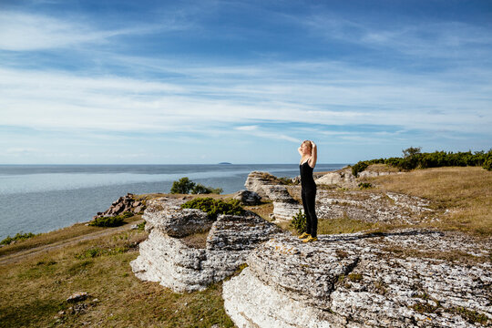 Woman standing on cliff by the sea