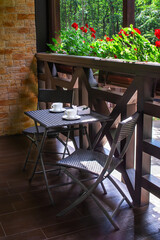 Nice terrace or balcony with small table, chairs and cups. Rest zone. Tea party for two.