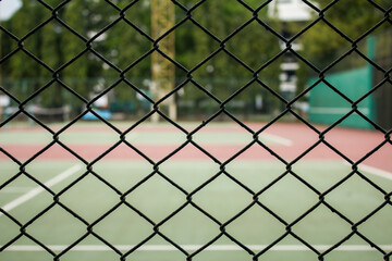 Fototapeta premium Close up the metal fence in front of a tennis court on the field
