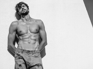 Portrait of sporty handsome strong man. Healthy athletic fitness model posing near white wall in...