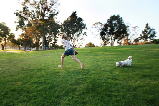 Little girl running with dog in park