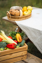 A box with a harvest of vegetables is on the street. Peppers, corn, broccoli, tomatoes and herbs inside the box. Autumn harvest.