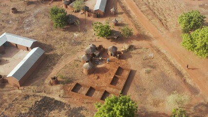 Drone shot of a traditional African round hut village during daylight. Orbit.