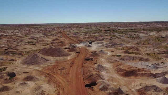 Aerial: Drone shot flying over opal mining works with large open pits below, in Coober Pedy, South Australian Outback