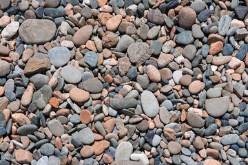 Small stones of different colors and sizes, pebbles on a pebble beach as a background.