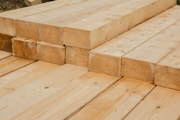 Piled wooden beams. Closeup big wooden boards. Stacked wooden beams of square section for house construction