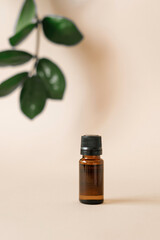 Glass oil bottle on a beige background, and a sheet of tropical plants with defocus. Organic natural cosmetics