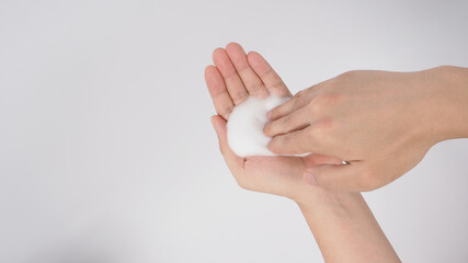 Hands washing gesture with foaming hand soap on white background.